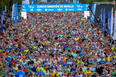 milhares de corredores passam o pórtico de largada da maratona de sevilla